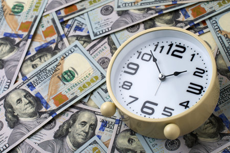 Close-up of alarm clock and stack of US dollar banknotes. Concept of time is money and the importance of financial efficiency. Business, finance, productivity, and wealthの写真素材