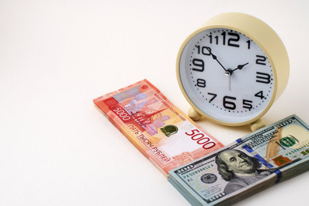 Close-up of desk clock stack of Russian Ruble banknotes and US Dollars Exchange. Time is money and importance of financial efficiency. Business, finance, productivity, and wealth management themesの写真素材