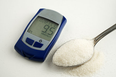 A close-up, high-angle shot of a digital glucose meter displaying a blood sugar reading next to a...