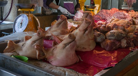 Pig heads on sale at a local farmer's market in Thailandの写真素材