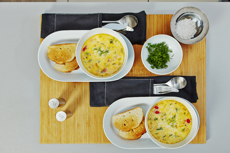 Served fish soup in a white plate, with toasts on a wooden tray.の写真素材