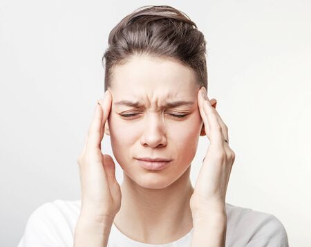 Young beautiful woman has headache, isolated on gray backgroundの写真素材