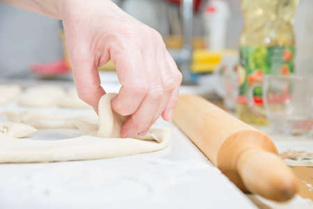 Old woman hand picking dough on table