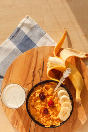 Sweet cornflakes breakfast cereal in the bowl with blackberry, cherry, banana and glass of milk on...