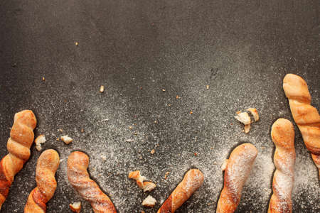 Three baguettes sprinkled with flour on black painted background. Top view with copyspaceの写真素材