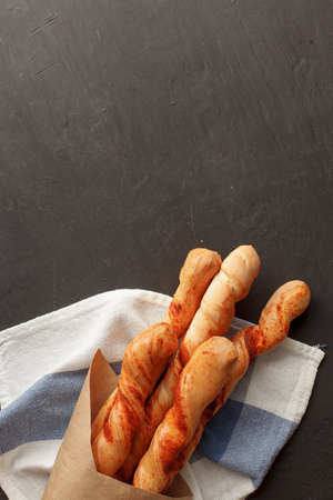 Three baguettes in paper packet on black painted background. Vertical photo. Top view with copyspaceの写真素材