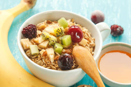 Oat flakes plate with honey, banana, egg, walnut on a turquoise wooden table. 45 degrees view of healthy oat flakes breakfast. Copy space. Selective focus.の写真素材