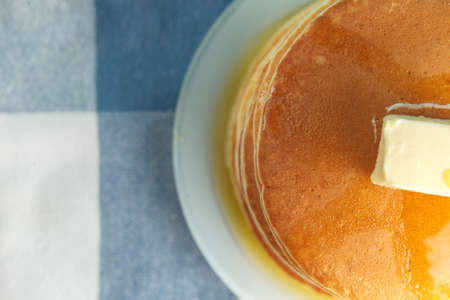 Close up photo of stack of pancakes with honey and piece of butter on plate which stands on napkin. Top view with copyspace. Concept of shrovetide treats. Selective focusの写真素材
