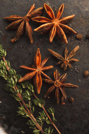 Five anise stars, two sprigs of thyme and black peper on old dark background. Selective focusの写真素材