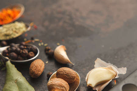 Several metal spoons with different spices on dark old table or background with copysapce for menu. Dark moody photo. Horizontal image. Selective focusの写真素材