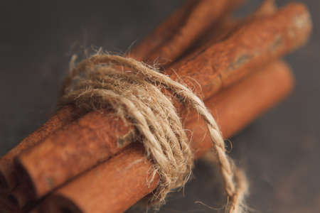 Some cinnamon sticks in bundle tied with jute twine on dark background. Selective focusの写真素材