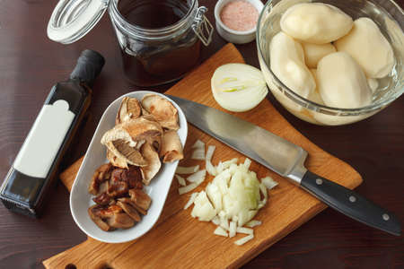 Ingredients for fried or boiled potato with mushrooms, onion and bouillon on tableの写真素材
