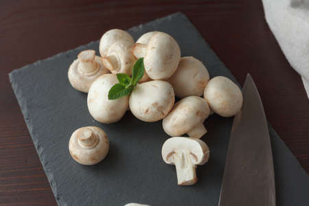 Mashrooms with sprig of mint on slate board with knife. Concept of vegetarian foodの写真素材