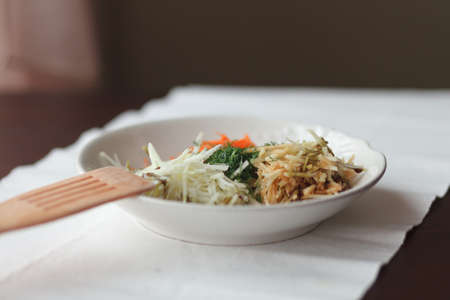Mix of grated carrot, apple, dill and kohlrabi for salad on table with napkinの写真素材