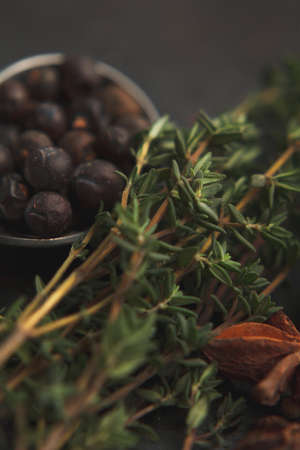 Anise star, some sprigs of thyme and juniper in metal teaspoon on old dark background. Selective focusの写真素材