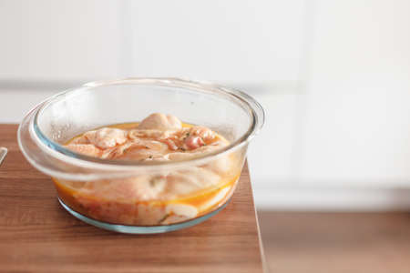 Glass cookware with a marinated chicken on table with copyspaceの写真素材