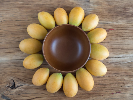 Sunflower shape made from marian plum and wooden bowl on wood backgroundの写真素材
