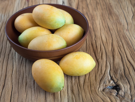Sweet marian plum in wooden bowl on wood tableの写真素材