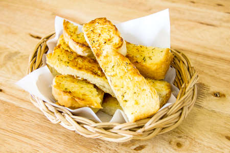 Garlic bread served in basket on wooden background