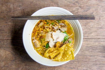 Hot spicy noodle soup with pork and dumplings in white ceramic bowl and chopstickの写真素材