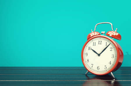 Red retro alarm clock on blue background with space, 3D renderingの写真素材