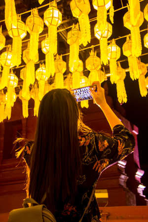 Female tourist taking picture of Northern Thai traditional lanterns with mobile smart phoneの写真素材