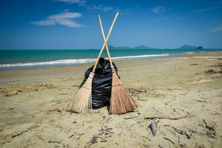 Cleaning day, broom and black garbage bag on the beach, Andaman Sea off the coast of, and part of, Phuket Province, southern Thailandの写真素材