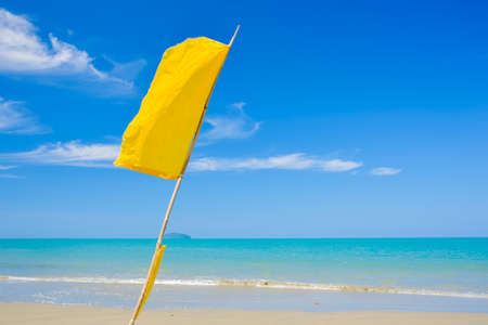 Yellow warning flag on the beach and blue sky at Phuket Thailand