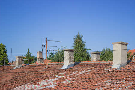 roof of an old house with antennas on top and smoke stackの写真素材