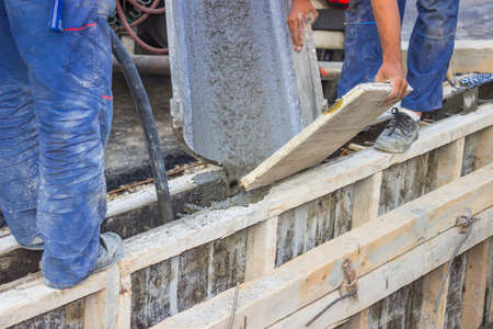 Concrete pouring from a truck for the construction of a new retaining wall at a building site.