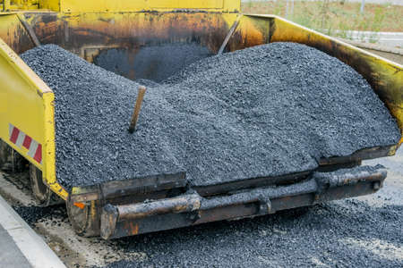 Back view of a large asphalt paving machine full of fresh asphalt.の写真素材