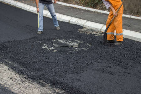 Engineer giving orders to asphalt worker during road constructionの写真素材