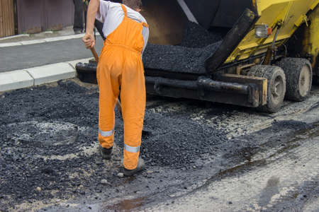 Asphalt paver machine during road construction, man is working, apply the first layer of asphalt.
の写真素材