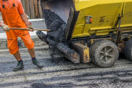 Asphalt paver machine during road construction, man is working, apply the first layer of asphalt.の写真素材