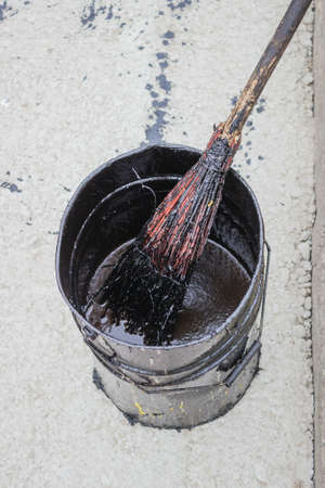 Bitumen Emulsion (Tack Coats) in metal bucket. Tack coat is a browny-black emulsion of bitumen that is applied to the prepared, existing surface before laying the new surface/wearing course. の写真素材