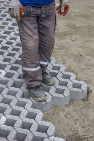 Worker paving new parking places, concrete grid pavers can be filled with soil for grass growth or aggregate for drainage applications.の写真素材