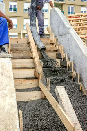manual workers pouring concrete steps with tube from truck mounted concrete pump
の写真素材