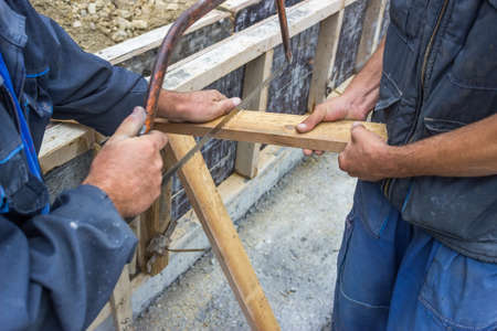 craftsman cutting wood board with a handsawの写真素材