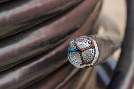 Cross section of electric black industrial underground cable on large wooden reel. Four core al cable. Selective focus and shallow dof.の写真素材