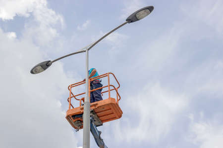 worker in lift bucket repair street light pole with double headの写真素材