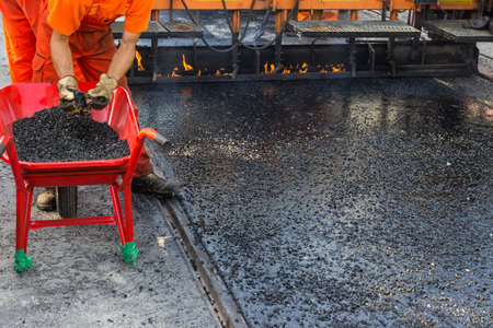Crew placing mastic asphalt road and pea gravel surfacing, laying of mastic surface. Selective focus and shallow dof.の写真素材