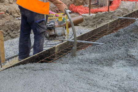 Worker hands using concrete vibrator for maximum strength and consistency in concrete. Selective focus and shallow dof.の写真素材