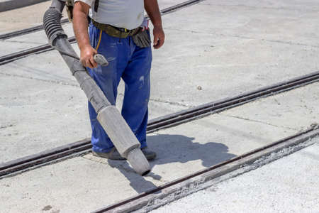 Worker with leaf-blower, cleaning out the dust for better asphalt adhesion, during tram track renewal works.の写真素材