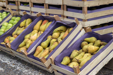 Pears and apples in wooden crates for sale at a street market. selective focus.の写真素材