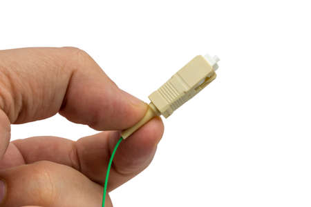 Fingers holding a fiber optics connector with fiber cable isolated on white backgroundの写真素材