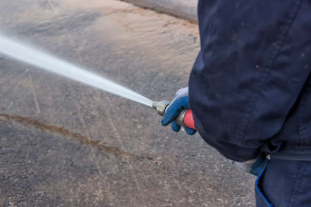 Using water hose to clean road by high pressure waterの写真素材