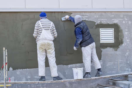 Workers plastering a outdoor wall with trowel.の写真素材