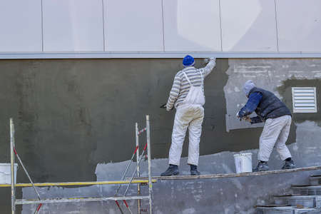 Workers plastering a outdoor wall with trowelの写真素材