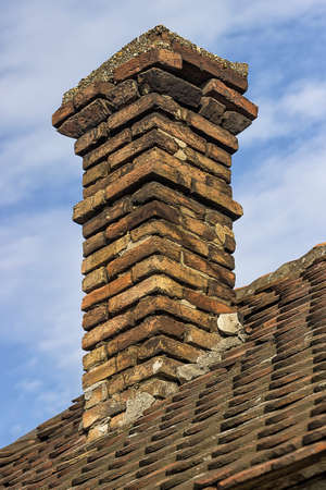 Old brick chimney with old tiles roof on a family houseの写真素材