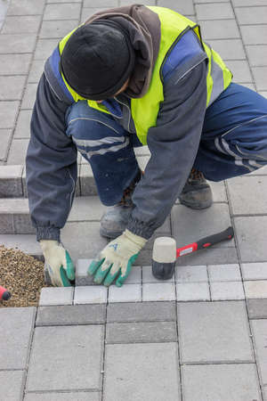 Construction worker installing sidewalk pavement with concrete brick.の写真素材